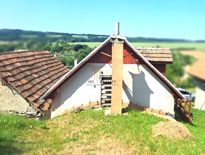 A cottage in Hontianske Trsťany with a traditional sloped roof and a scenery of green landscape.