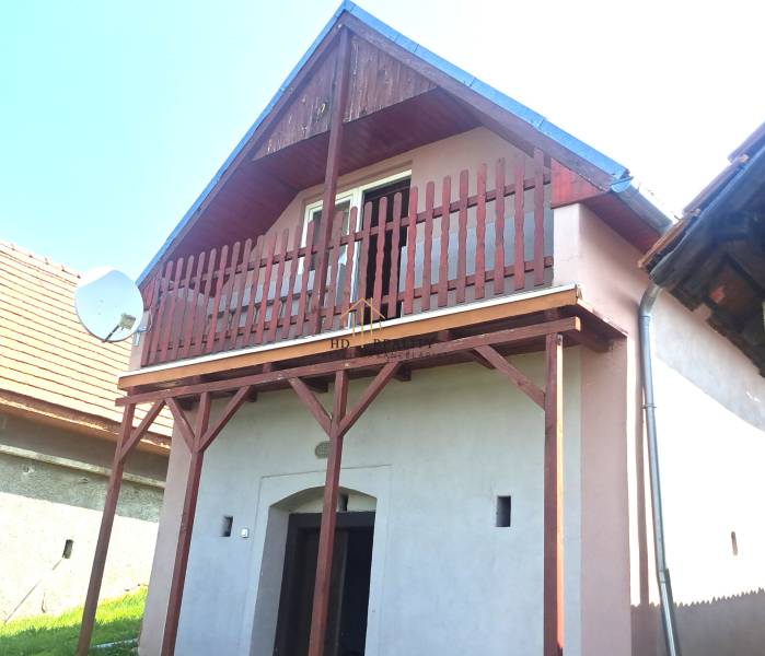 A cottage in Hontianske Trsťany with a wooden balcony and a satellite dish.