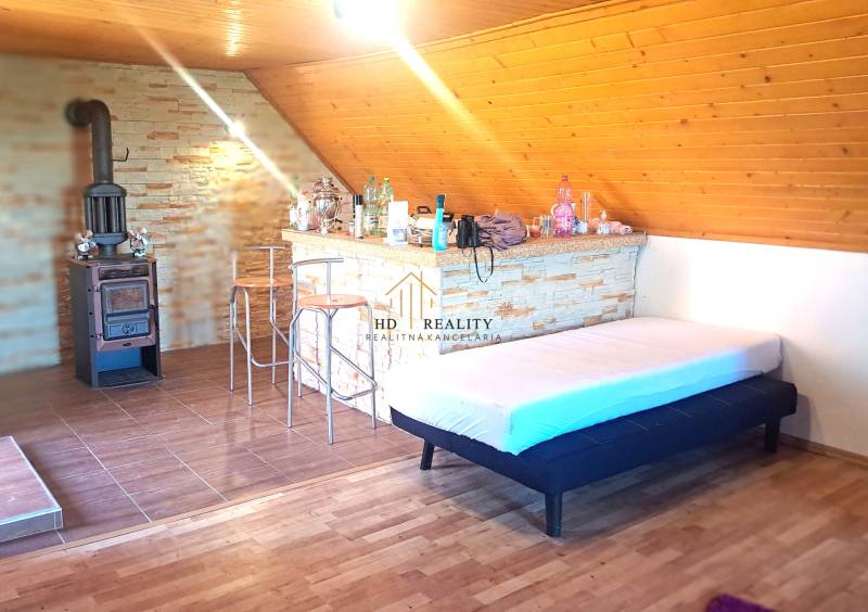 Interior of a cabin with a fireplace, a bar counter, and a floor with a wooden decor.