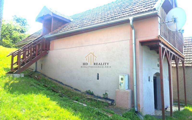 A cottage in Hontianske Trsťany with an outdoor staircase, lawn, and satellite dish.