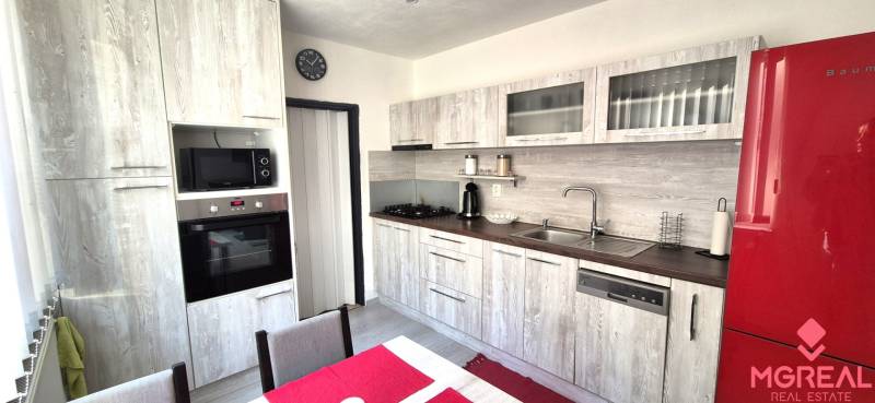 A kitchen in a 2-room apartment with a wooden decor and a red refrigerator.