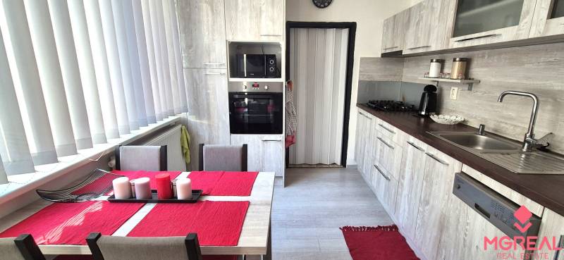 A kitchen with a dining table, white blinds, and a kitchen unit in a 2-room apartment.