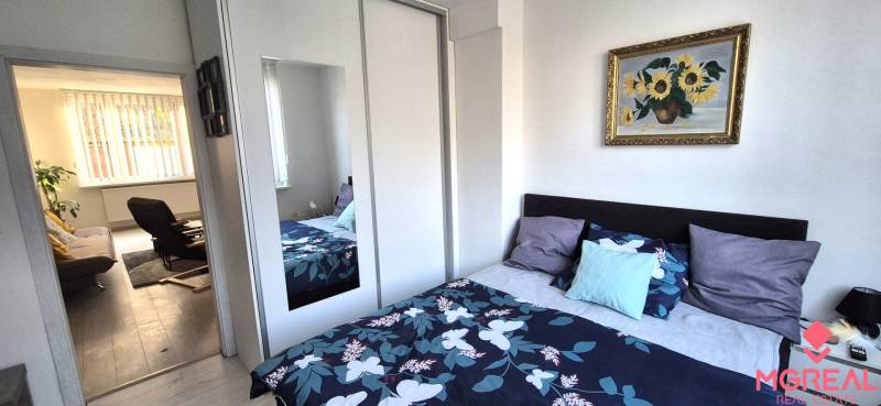 A bedroom with a colorful bed and wardrobe in a 2-room apartment, leading to the living room.