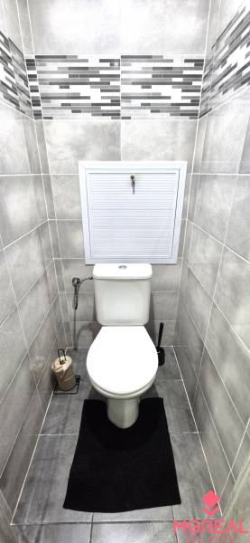 A toilet in a 2-room apartment with tiles in light shades and geometric details.