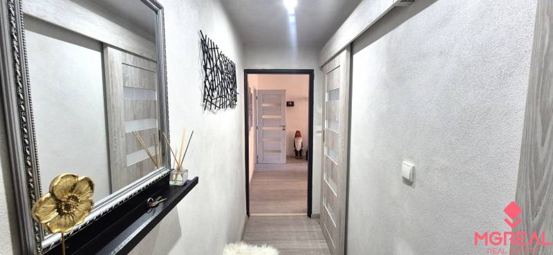A hallway in a 2-room apartment with a wooden decor floor and a decorative mirror.