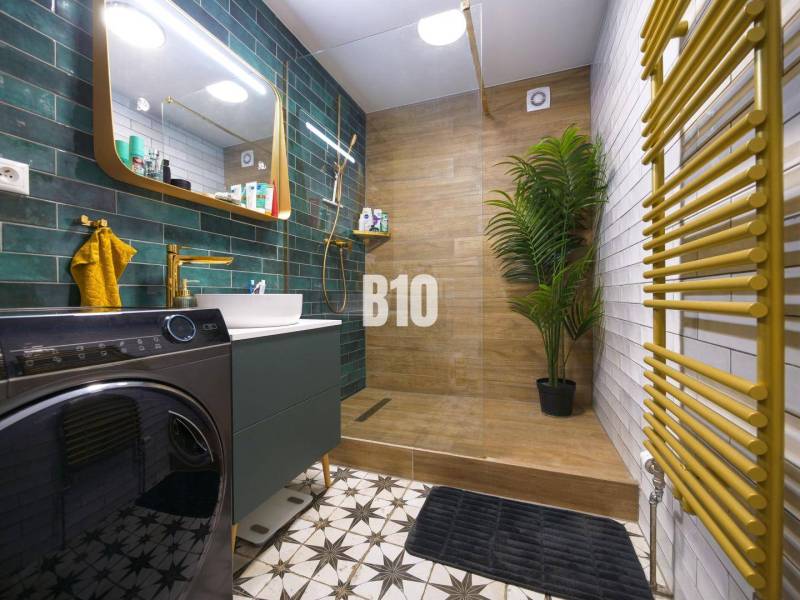 Bathroom in a 3-room apartment with a sink, washing machine, green tiles, and a floor with a wooden decor.
