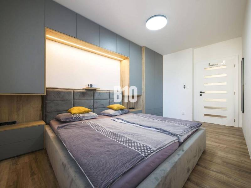 A bedroom in a 3-room apartment with a bed, wardrobes, and a floor with a wooden decor.