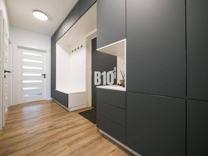 A hallway in a 3-room apartment with storage spaces and a floor with a wooden decor.