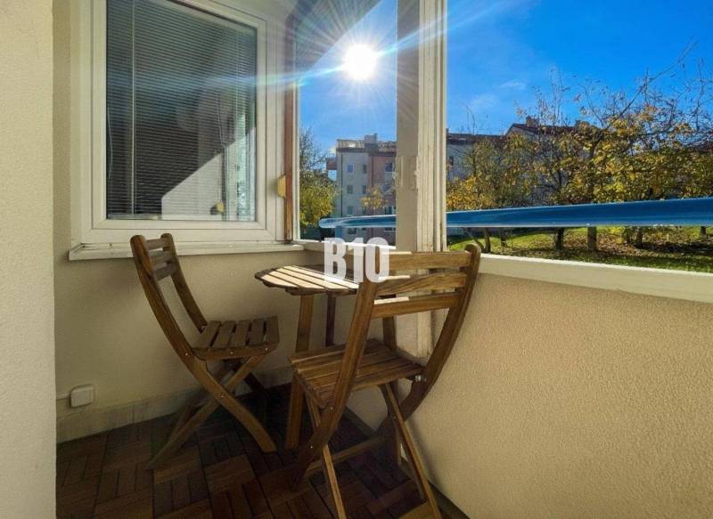 Balcony of a 3-room apartment in Nitra with wooden furniture and a view of greenery.