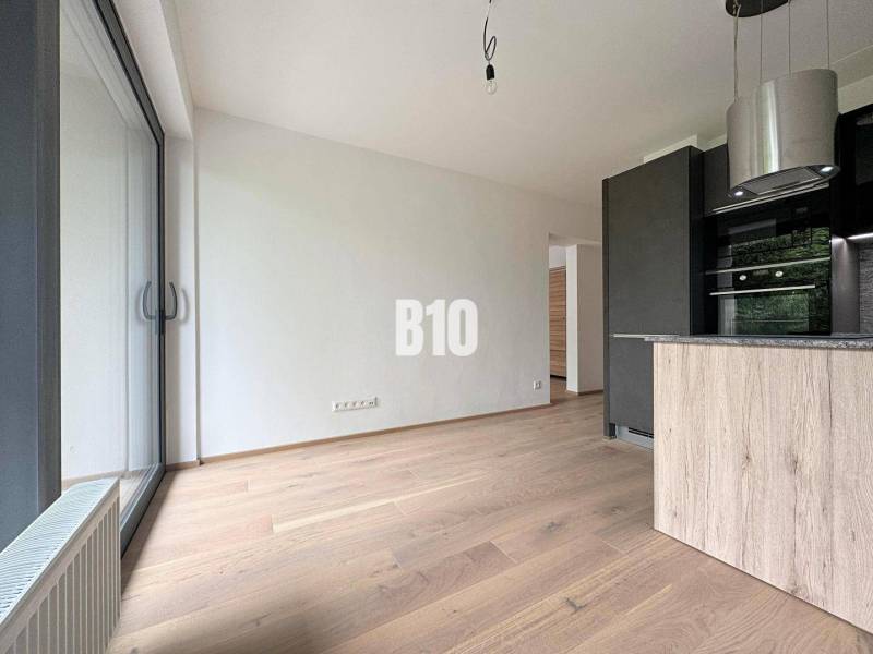 A bright interior of a 2-room apartment with large windows and wooden flooring.
