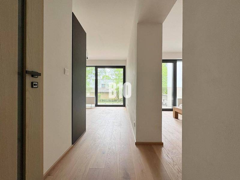 A bright interior of a two-room apartment with wooden flooring and large windows.