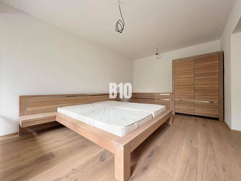 Bedroom in a 2-room apartment with a wooden bed and a wardrobe on a wooden floor.