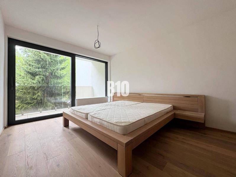 Bedroom in a two-room apartment with wooden flooring and a large window to the terrace.