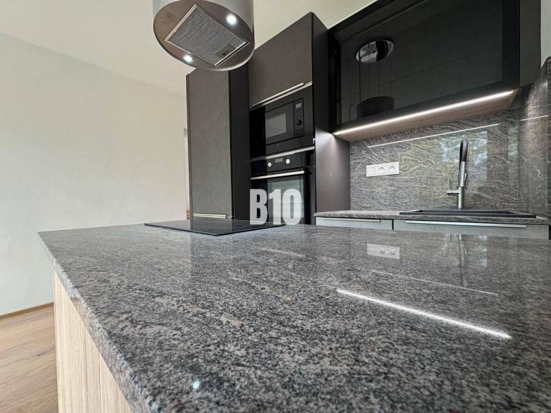 A kitchen in a 2-room apartment with a marble countertop and modern equipment.