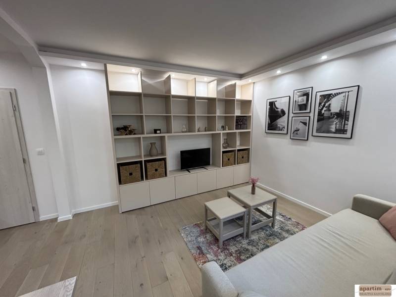 Living room in a 2-room apartment with a sofa, shelf, and floor with wooden decor.