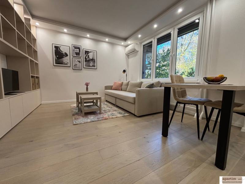 Living room in a two-room apartment, large sofa, table, wooden decor flooring.