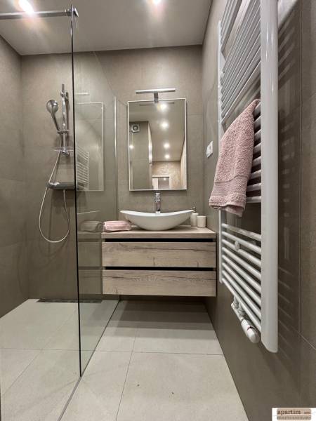 Bathroom in a 2-room apartment with a sink, shower, and a towel on the radiator.