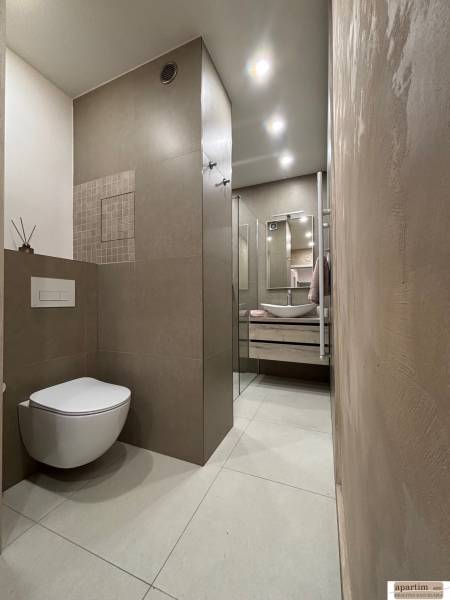 Bathroom in a 2-room apartment with a shower, sink, and wall-mounted toilet.