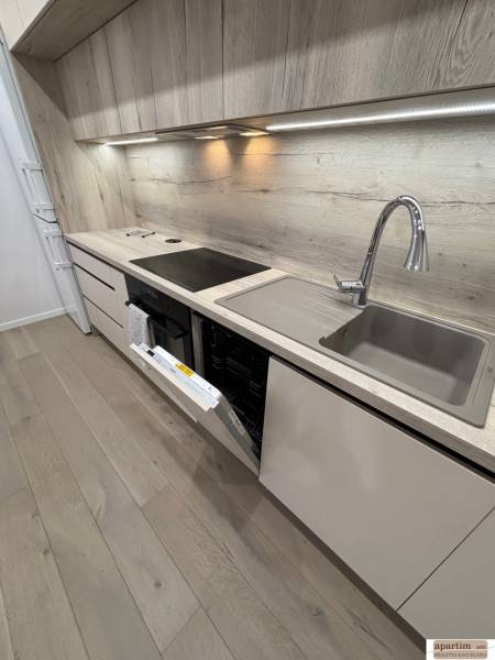 Corner kitchen in a 2-room apartment with a dishwasher and flooring with a wooden decor.