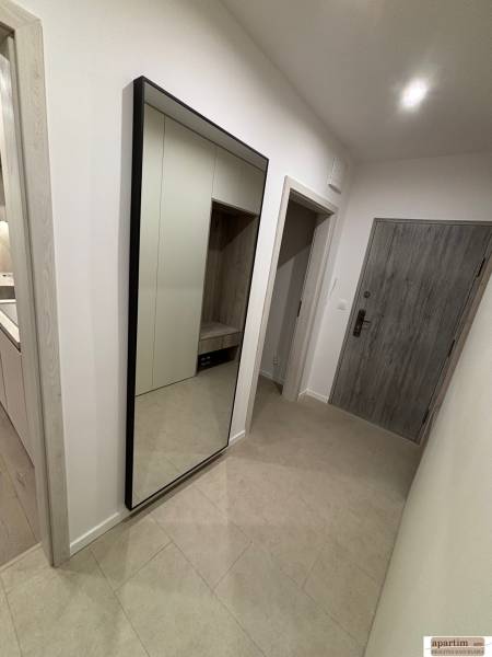 A hallway in a 2-room apartment with a large mirror, a cabinet, and tiles.