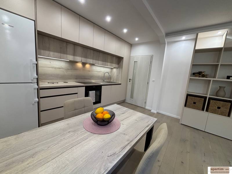 A kitchen in a 2-room apartment with a wood-patterned floor and built-in appliances.