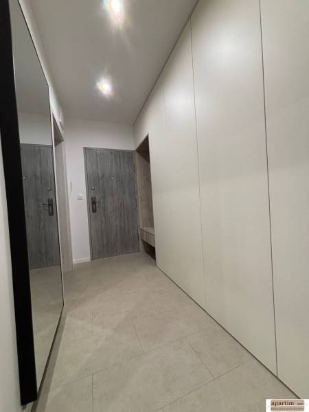 Entrance hallway of a 2-room apartment with white cabinets and a mirror on the wall.