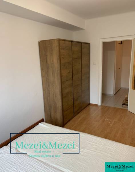 A wardrobe with a wooden decor in a 2-room apartment. White wall and floor with wooden decor.