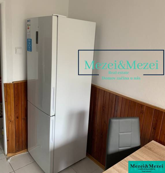 Kitchen in a 2-room apartment, refrigerator, wooden paneling, gray chair, dining table.