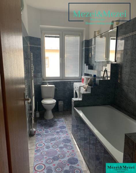 Bathroom in a 2-room apartment with a bathtub, washing machine, and dark tiles.
