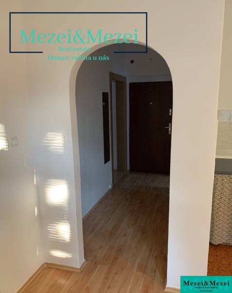 Interior of a 2-room apartment with a wood-patterned floor and an arched entrance.