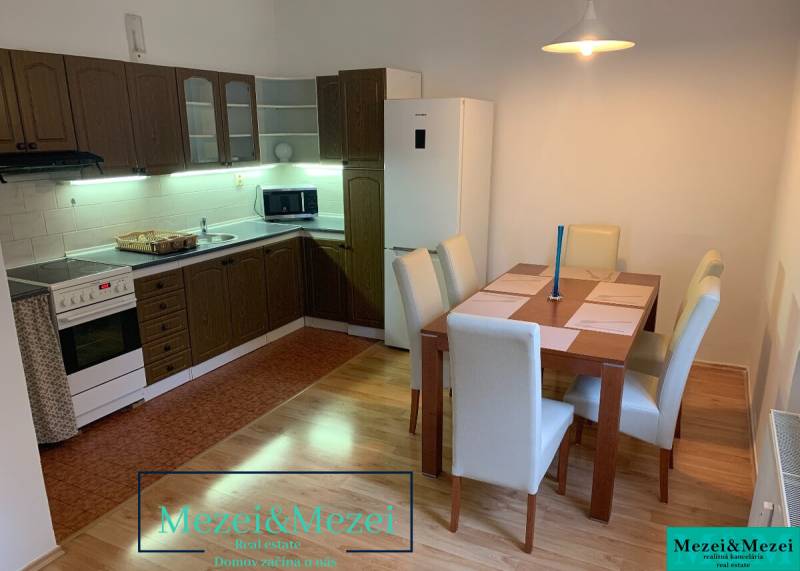 The kitchen of a two-room apartment with a corner unit, a dining table, and a floor with a wooden decor.