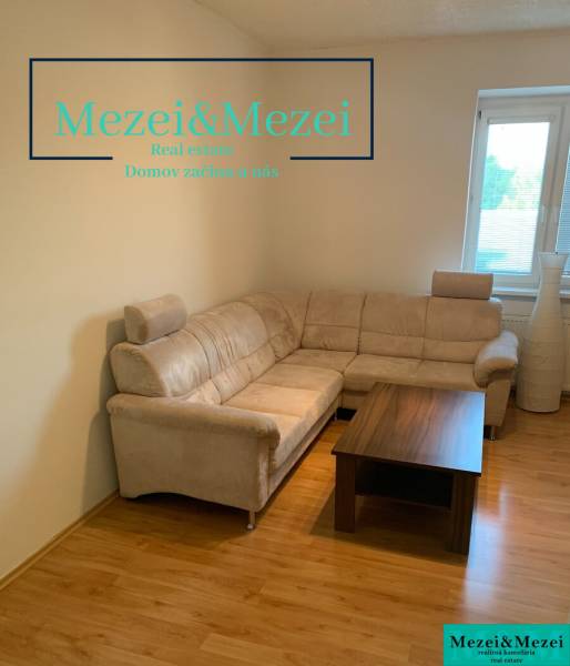 Living room in a two-room apartment with a corner sofa and a table on a floor with a wooden decor.