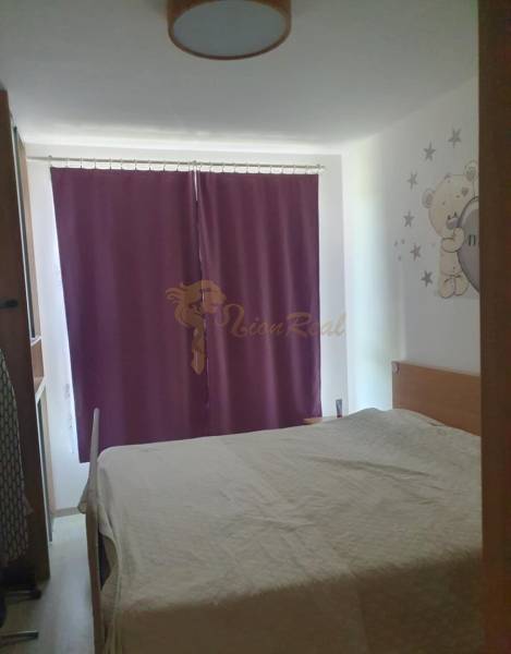 A bedroom with purple curtains, a children's theme, and a wooden decor floor in a two-room apartment.