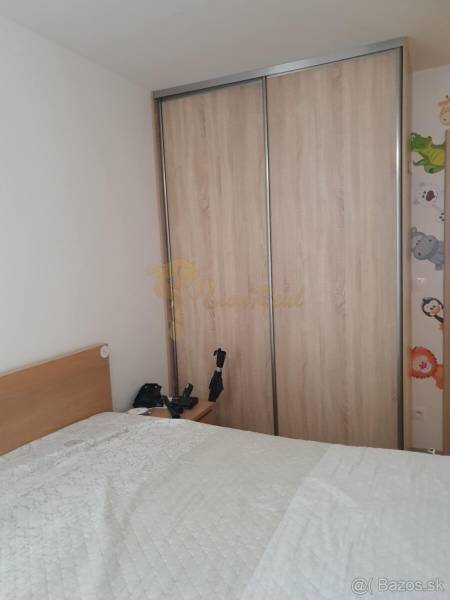 Bedroom in a 2-room apartment, sliding wardrobe, bed with a blanket, and a nightstand.