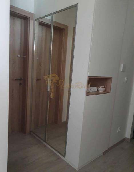 A hallway with a large mirror and a floor with a wooden decor in a 2-room apartment.