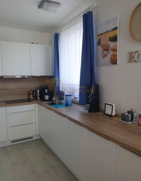 A kitchen in a 2-room apartment with white cabinets and a wood-patterned floor.
