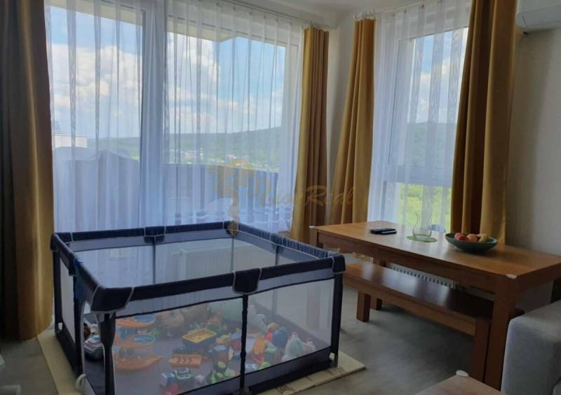 A playpen and a table in the living room of a two-room apartment with a view.