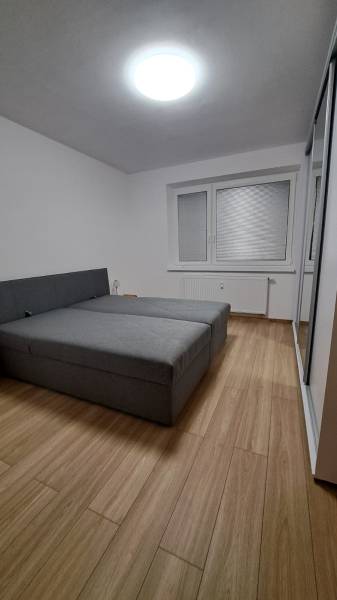 Bedroom in a 2-room apartment with a wooden decor floor and a large bed.
