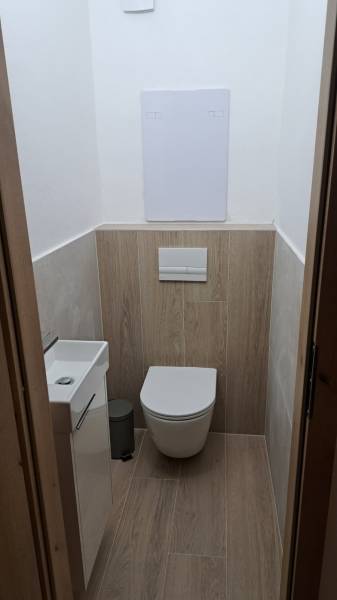 A toilet with a wooden floor decor in a 2-room apartment, simple design.
