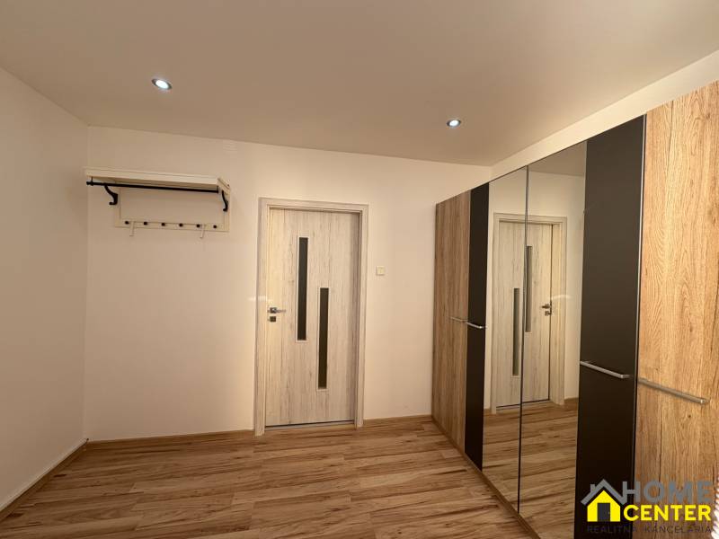 A room in a 3-room apartment with a floor featuring a wooden decor and a mirrored wardrobe.