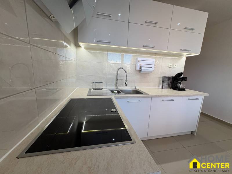Elegant kitchen in a 3-room apartment with white cabinets and an induction cooktop.