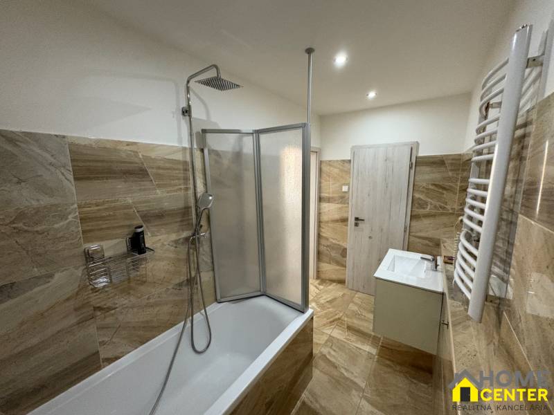 A bathroom in a 3-room apartment with a bathtub and a shower, tiled with light tiles.