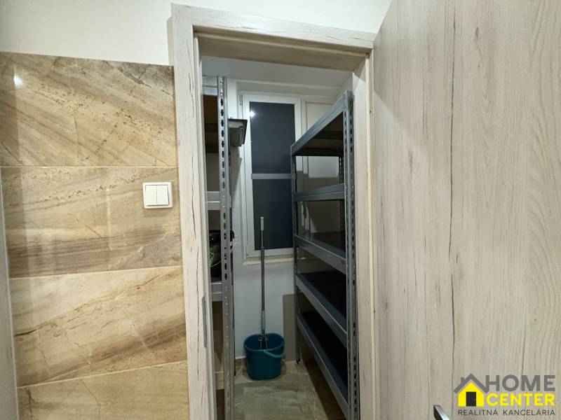 A small storage room in a 3-room apartment with shelves and a bucket.