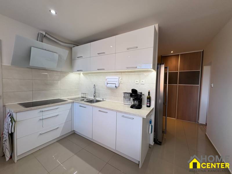 A kitchen unit in a 3-room apartment with a wooden decor floor and appliances.