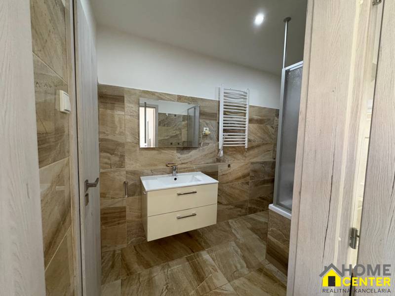 A bathroom in a 3-room apartment with light tiles and a hanging cabinet.
