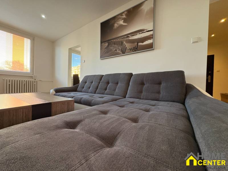 A bright living room with a comfortable sofa and a large window in a three-room apartment.