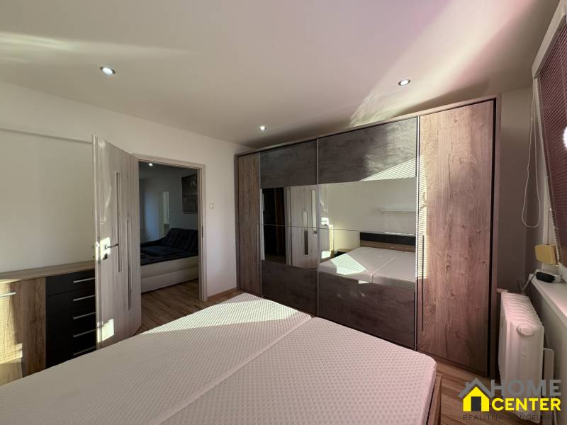 A bedroom with a built-in wardrobe and flowing natural light in a 3-room apartment.