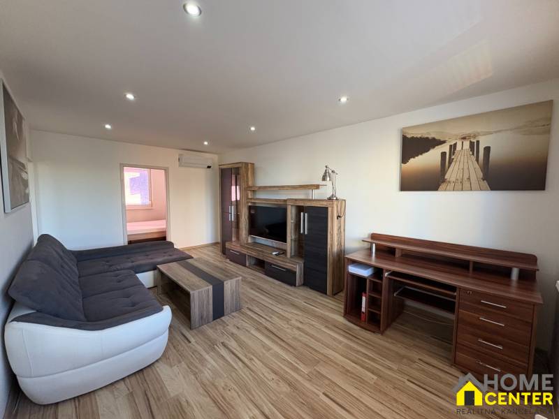 Living room in a three-room apartment with a wooden decor floor and a comfortable sofa set.