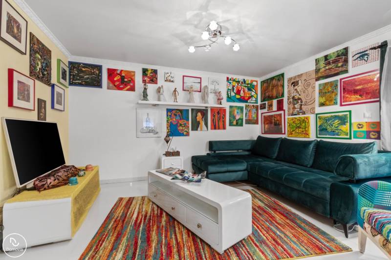 A colorfully decorated living room of a family house with a green sofa and artworks on the walls.