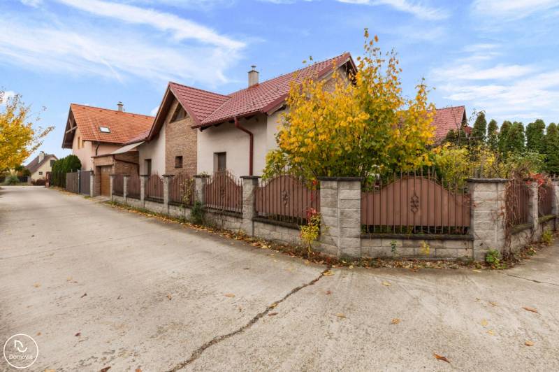A family house on Košariská Street in Rovinka with a brick roof and fence.